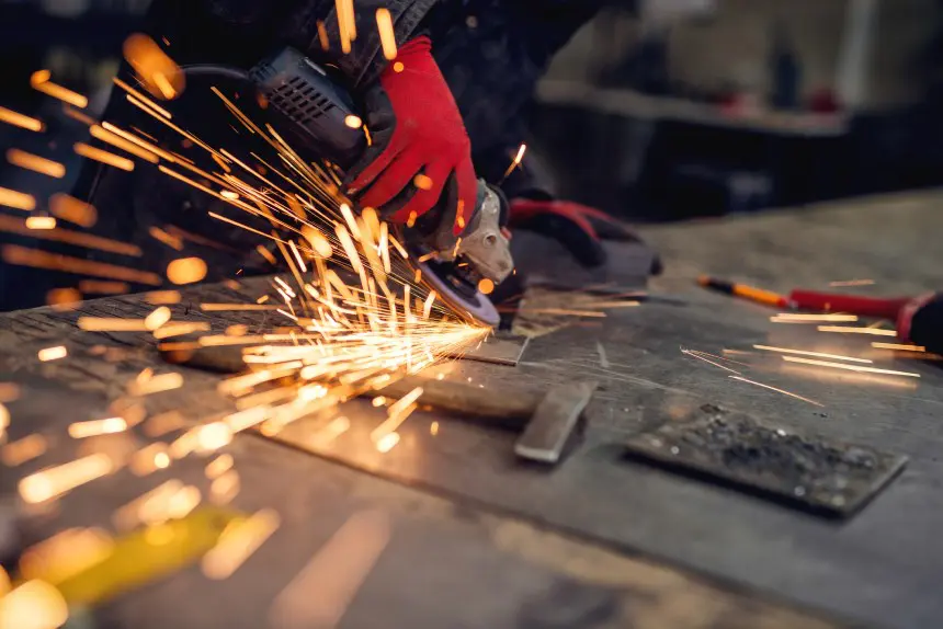 Craftsman Sawing Metal, Sparkles Around Workshop.